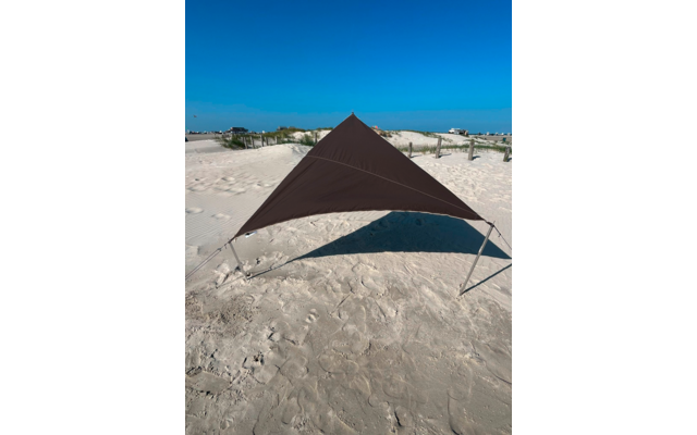 Dreieckiges braunes Tuch an Metallpfosten auf Sandstrand; Fußspuren, Dünen mit Gras, Meer am Horizont, klarer blauer Himmel
