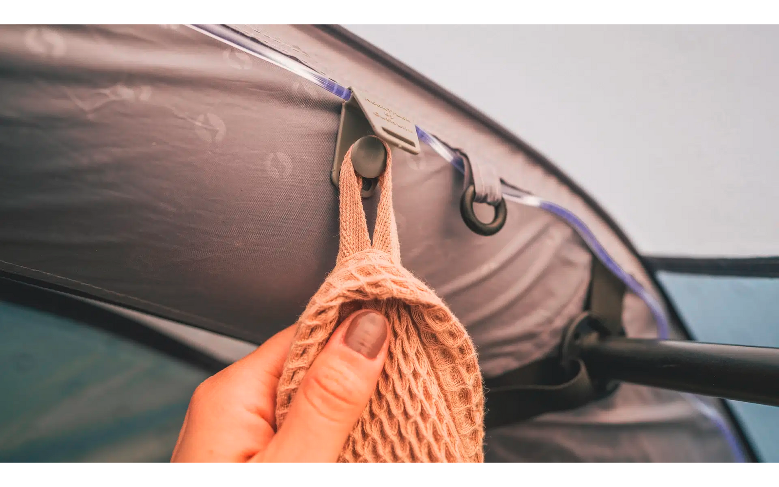 Ein geflochtener Korb hängt an einem Haken unter einem Zeltstoff