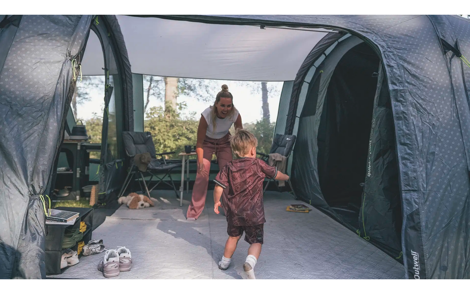 Frau öffnet Zeltöffnung, draußen zu sehen Bäume und Himmel