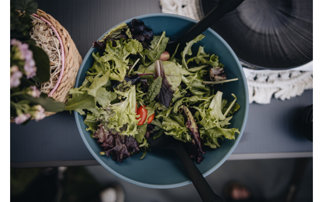 Grüner Salat in einer blauen Schüssel mit einem schwarzen Besteckstück