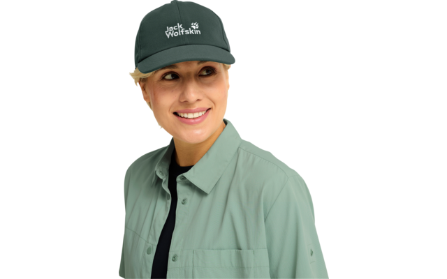 Person mit grünem Baseballcap mit 'Jack Wolfskin'-Logo, hellgrüner Hemdjacke und schwarzem Shirt, lächelnd, nach links blickend