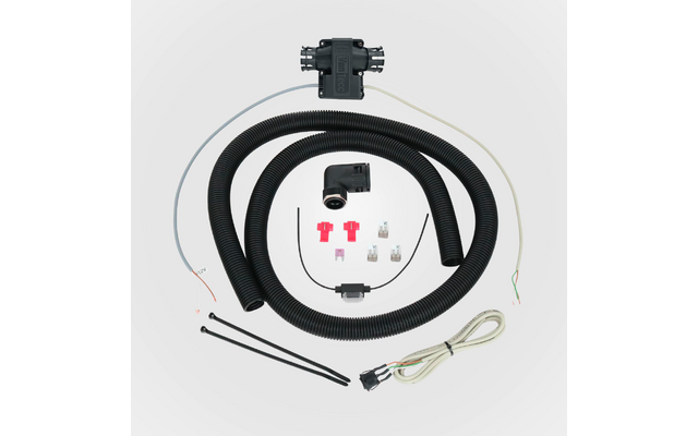 Boîtier en plastique noir, deux gaines ondulées noires enroulées, connecteur coudé noir, câble blanc avec prise, plusieurs fils fins, trois raccords rouges, deux fusibles à lame transparents, trois colliers de serrage noirs, petit élément noir