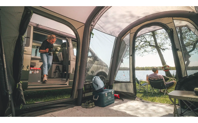 Person sitzt vor einem Zelt und blickt durch ein Fenster nach draußen auf Bäume