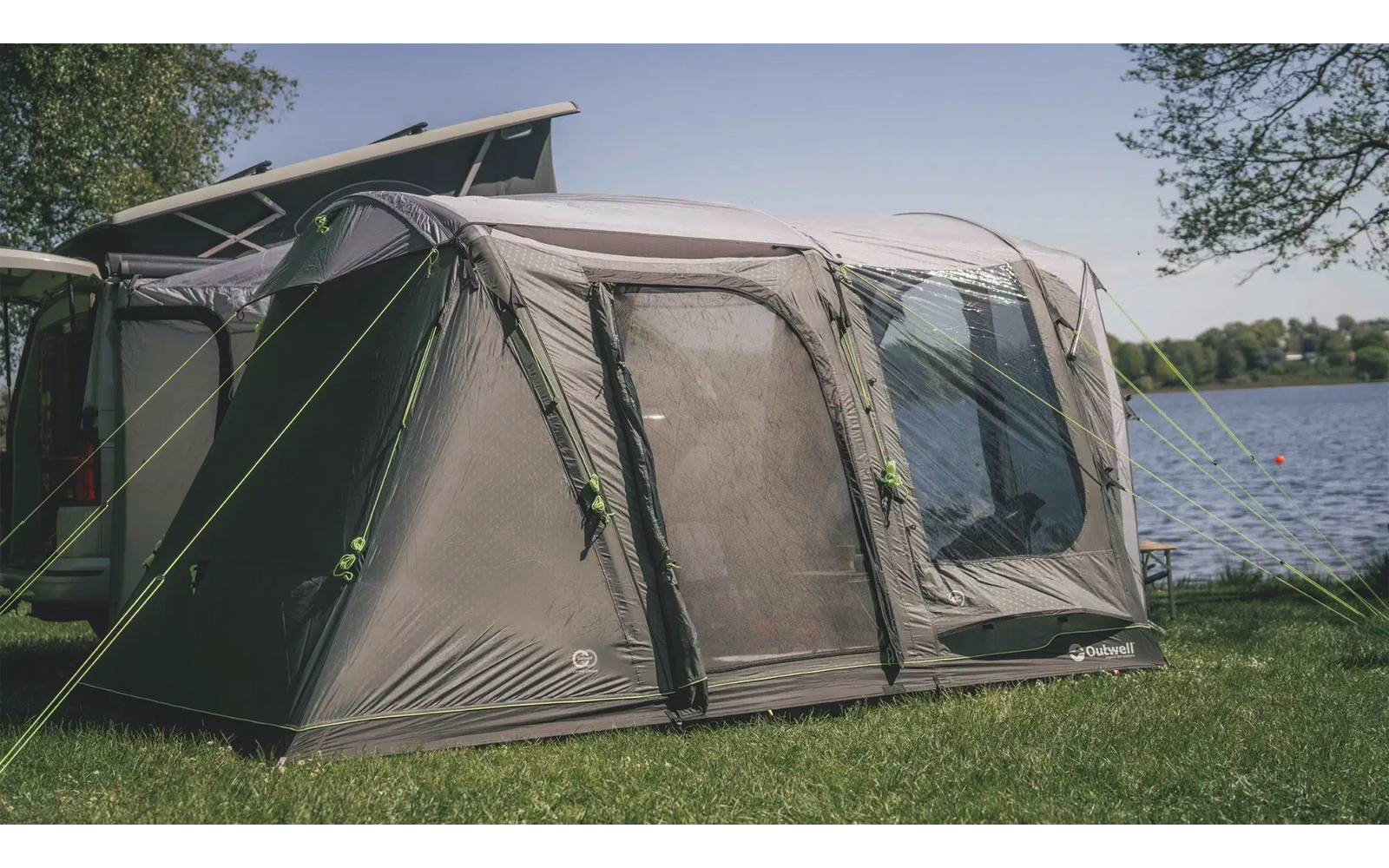 Grünes Zelt steht auf einer Wiese neben einem See