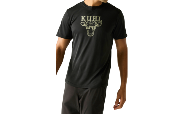 Stehender Mann in schwarzem T‑Shirt mit beigem "KUHL"-Schriftzug und Kuhkopf-Grafik sowie dunkler Hose vor hellem Hintergrund