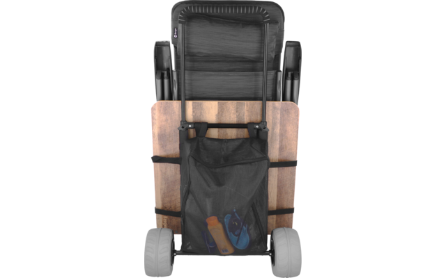 Vista trasera de una silla plegada con listones de madera horizontales, armazón metálico negro, dos ruedas y un bolsillo de malla negro que contiene una botella naranja y sandalias azules