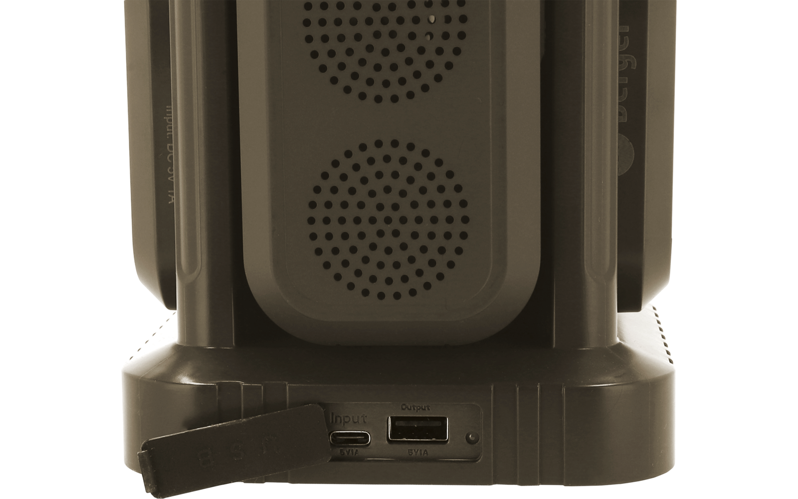 Parte inferior de un dispositivo negro con dos rejillas de altavoz redondas, soportes verticales, puertos visibles (USB‑C y ranura) y una tapa de goma colgando