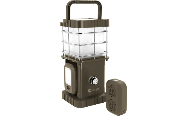 dispositivo rectangular verde oliva con jaula metálica alrededor de una zona luminosa cuadrada transparente, asa abatible en la parte superior, perilla redonda en el frente, panel de luz lateral rectangular y dispositivo rectangular separado con dos rejillas circulares