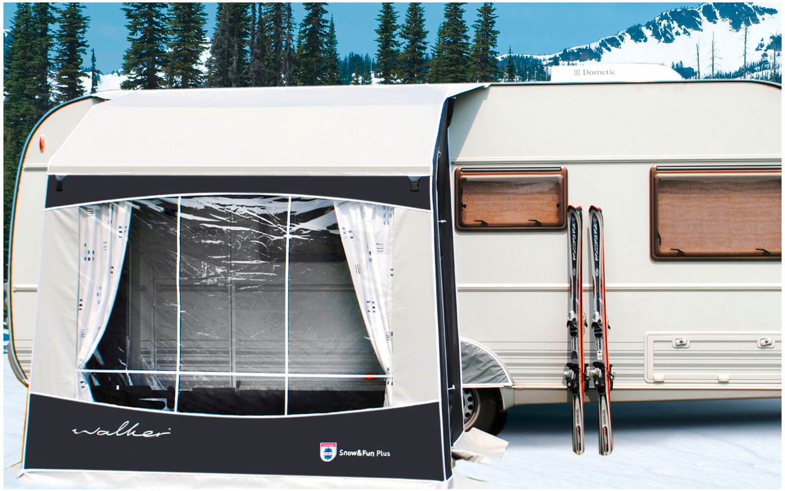 Caravan with attached awning in a snowy landscape, trees and mountains in the background