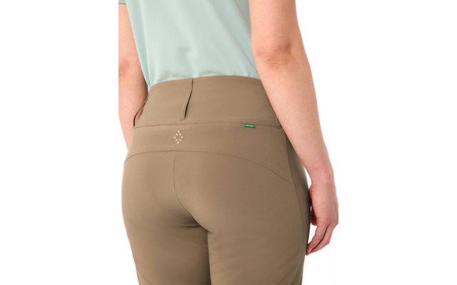 Rückenansicht einer Person von Taille bis zu den Oberschenkeln, mintgrünes Oberteil, taupefarbene Hose mit hinterer Naht und kleinem grünen Etikett am Bund, sichtbarer Unterarm