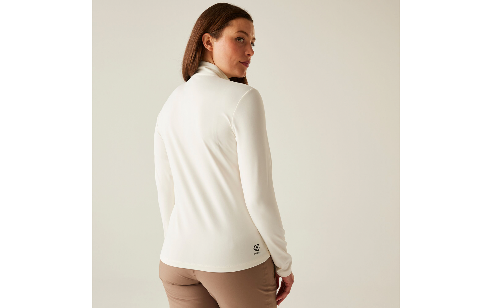 Femme aux longs cheveux bruns portant un pull blanc, regard par-dessus l'épaule vers l'arrière