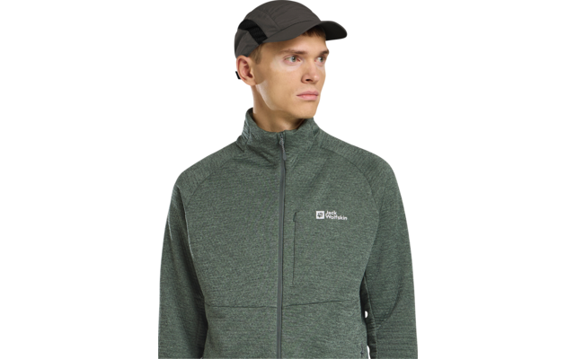 Person mit dunkler Kappe und grüner Jacke mit Reißverschluss und sichtbarem Markenlogo, schaut nach rechts