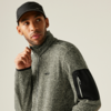 Mann trägt grauen Pullover und schwarze Mütze, schaut nach rechts