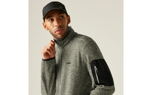 Mann trägt grauen Pullover und schwarze Mütze, schaut nach rechts