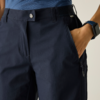 Dunkelblaue Hose mit Druckknopf und Bund, Hand in seitlicher Hosentasche, Reißverschlusstasche am Oberschenkel, blau gestreiftes Oberteil am Bund sichtbar, Smartwatch am Handgelenk