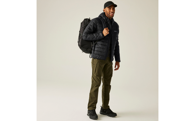 Mann trägt schwarze Jacke, schwarze Mütze, grüne Hose und schwarzen Rucksack
