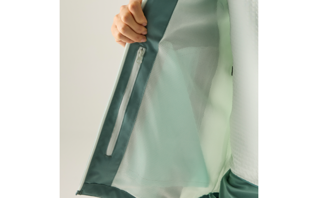 Hand hält das geöffnete Innenfutter einer hellgrünen Jacke mit Reißverschluss-Innentasche und Netzstoff