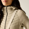 Brustansicht einer Person in beiger Steppjacke mit Reißverschluss, hohem Kragen und diagonalem Träger über der Schulter; dunkle Haare sichtbar