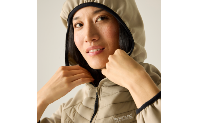 Nahaufnahme einer Person mit dunklen Haaren, die den Reißverschluss einer beigefarbenen gestepp­ten Kapuzenjacke hält; sichtbares Markenlogo Regatta Great Outdoors; heller Hintergrund