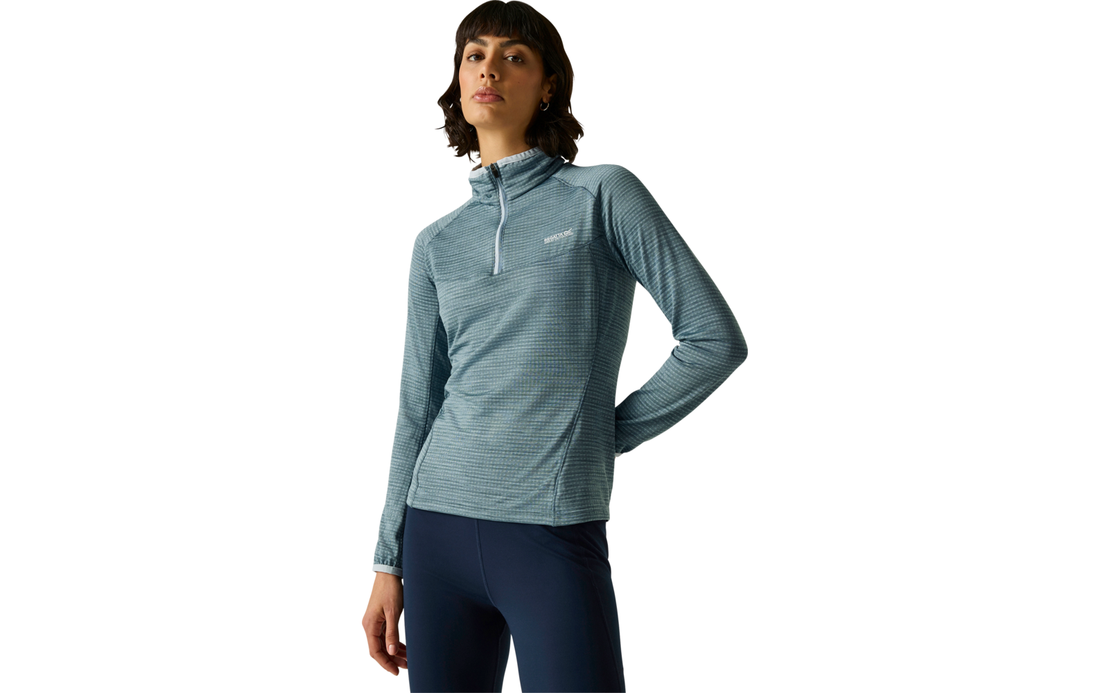 Personne debout portant un haut à manches longues bleu-gris rayé avec une courte fermeture éclair à l'avant et des leggings bleu foncé sur un fond uni clair
