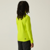 Persoon van achteren met lange dreadlocks, draagt een neon geelgroene longsleeve en zwarte broek voor een lichte achtergrond