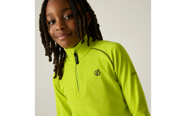 Persoon met gevlochten haar draagt een neongeel-groen shirt met lange mouwen en korte rits, klein logo op de borst, tekst op de mouw, lichte effen achtergrond