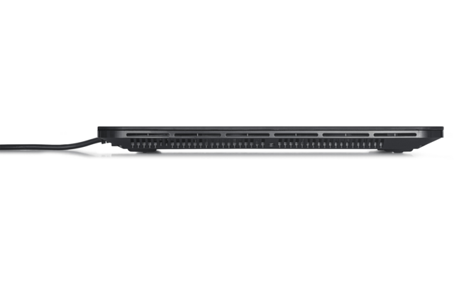 Zijaanzicht van een gesloten zilverkleurige laptop met ventilatiesleuven en een zwarte kabel die in een aansluiting is gestoken