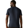 Achteraanzicht van een persoon met kort haar die een donkerblauw T-shirt en een polshorloge draagt voor een lichtbeige achtergrond