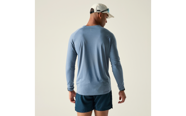Person von hinten, trägt hellblaues Langarmshirt, dunkelblaue Shorts und weiße Kappe mit Sonnenbrille; heller neutraler Hintergrund