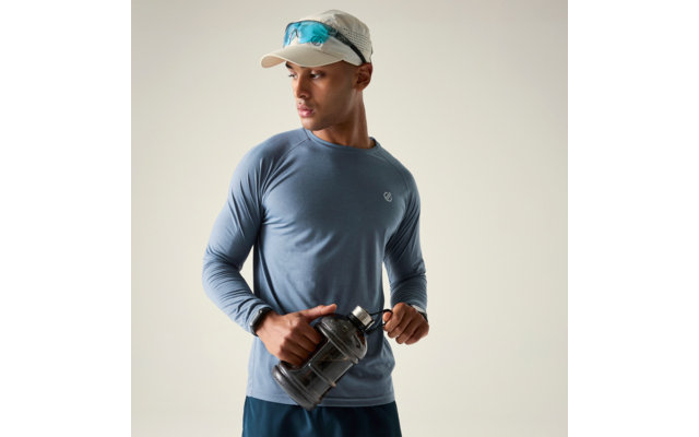 Mann in langärmeligem Sportshirt und Cap mit aufgesetzter Sonnenbrille, hält große Trinkflasche und blickt nach rechts