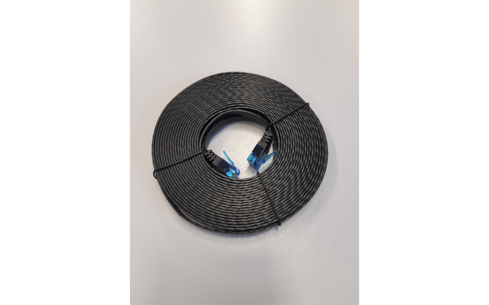 Câble noir enroulé en cercle sur une surface gris clair