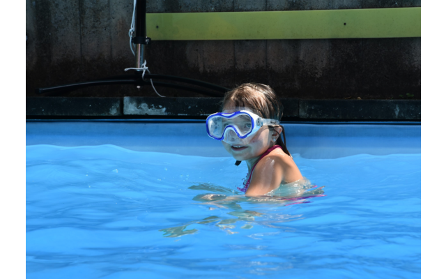 Kind mit Schwimmbrille im Wasser eines Schwimmbeckens