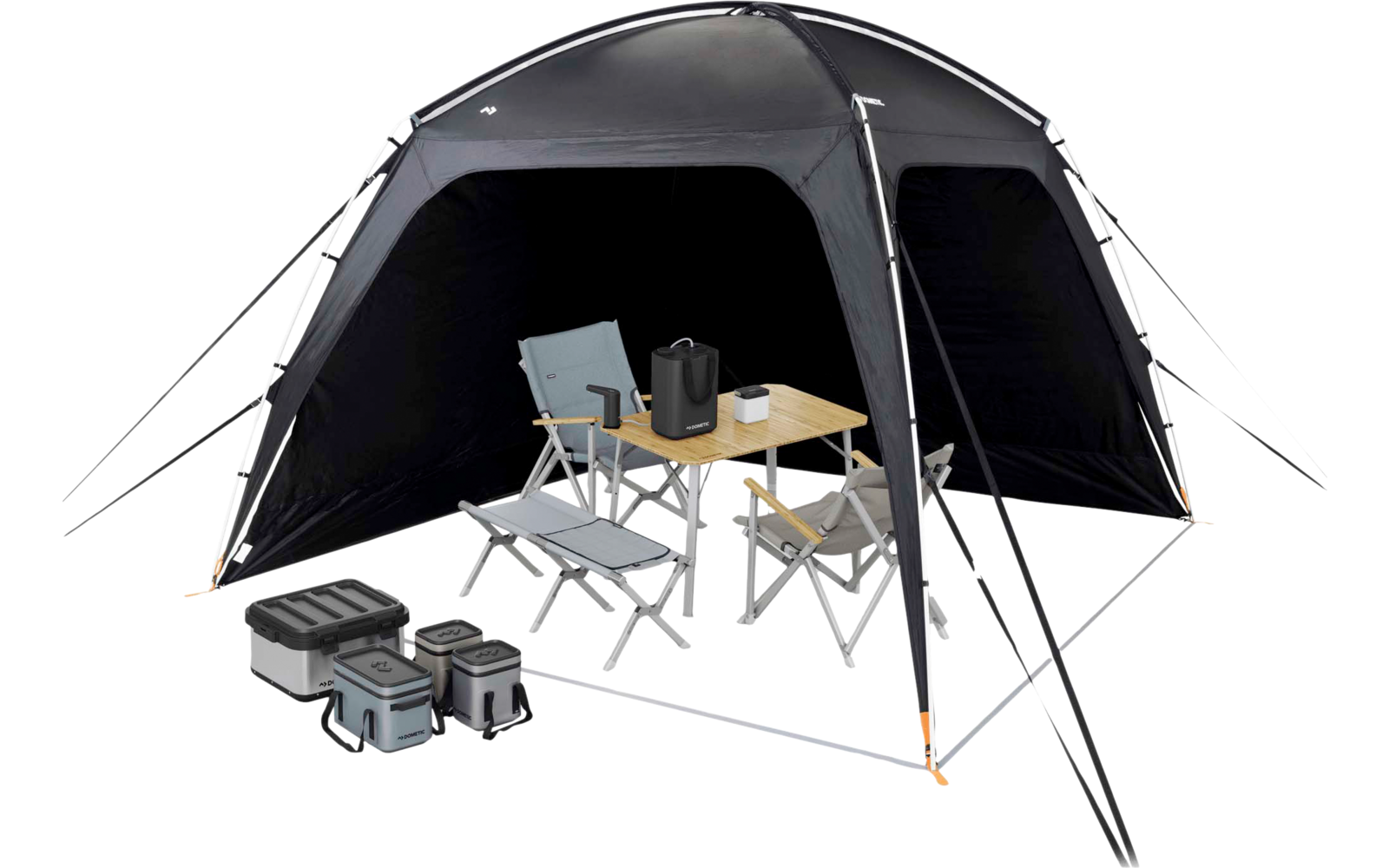 Vrijstaand zwart tent met open ingang; binnenin een opvouwbare houten tafel met een waterkoker en een mok en twee vouwstoelen; links drie opgestapelde boxen; tentstokken en scheerlijnen met oranje punten