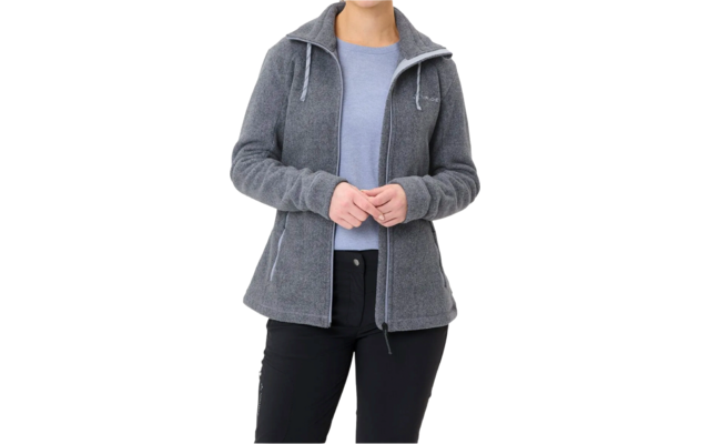 Frau mit grauer Jacke und blauer Bluse, die Hände vor dem Bauch zusammenhält