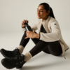 Persona seduta a terra con giacca e leggings, tiene una borraccia