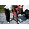 Personne tenant une chaise pliante rouge à côté d’un camping-car blanc sur un tapis extérieur gris à motifs