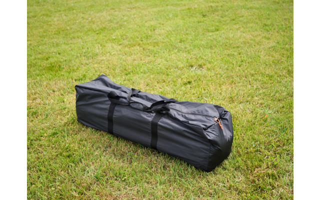 dunkelgraue, längliche Tasche mit schwarzen Tragegurten liegt auf grünem Gras