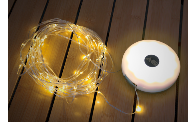 String lights with yellow LED bulbs and round white base on wooden floor