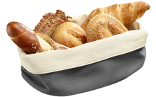 Cloth-lined basket with assorted bread rolls and a croissant, including a pretzel-style roll, a sesame-topped roll, and slices of multigrain bread