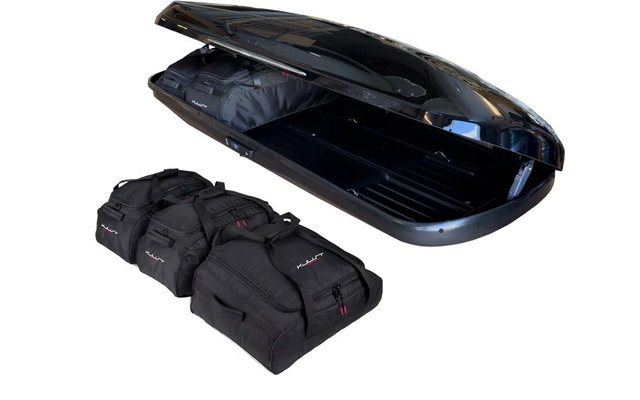 Geöffnete schwarze Dachbox mit drei schwarzen Reisetaschen daneben