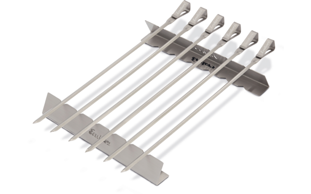 Sieben flache silberne Metallspieße mit abgeflachten Griffen liegen parallel auf einem Metallhalter