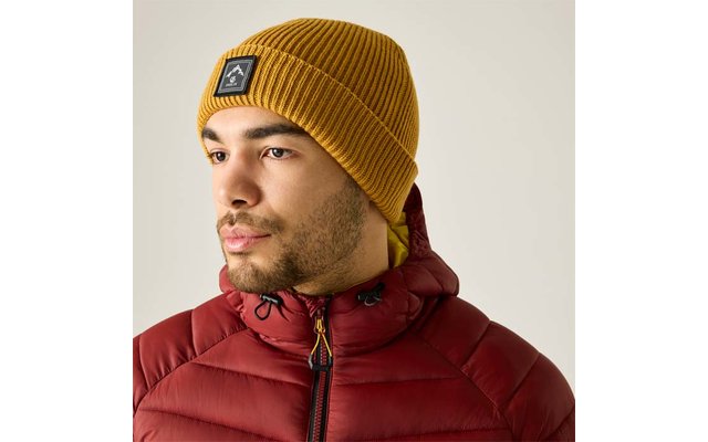 Persona con gorro de punto amarillo y chaqueta acolchada roja, barba corta, mirada hacia la izquierda