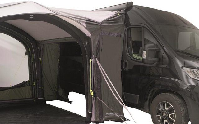 Black van with a dark inflatable side awning attached; open entrance, guy lines, and a visible wheel