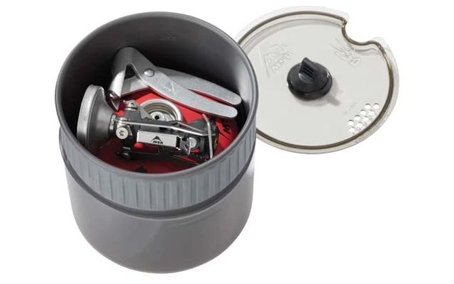 Gray round plastic container with removed lid; inside a folded silver metal device with visible burner and red base; transparent lid with black knob lies beside it