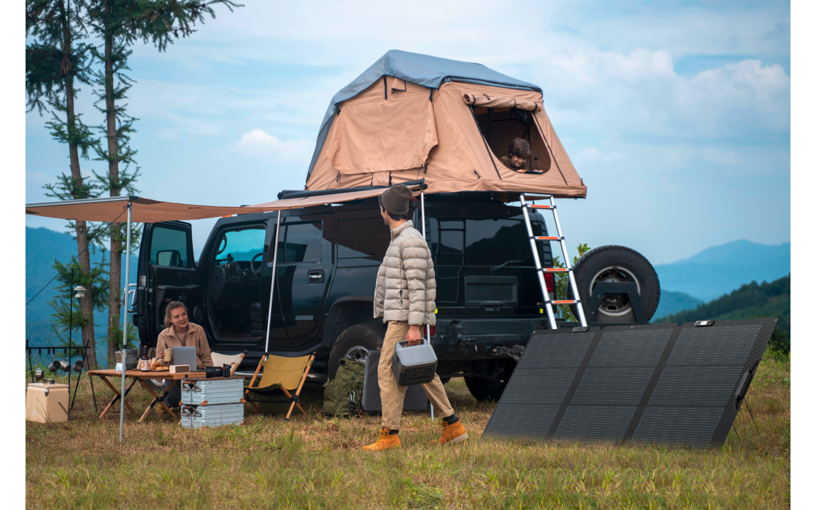 Campingfahrzeug mit Dachzelt auf einer Wiese, zwei Personen, Solarzellen liegen auf dem Gras