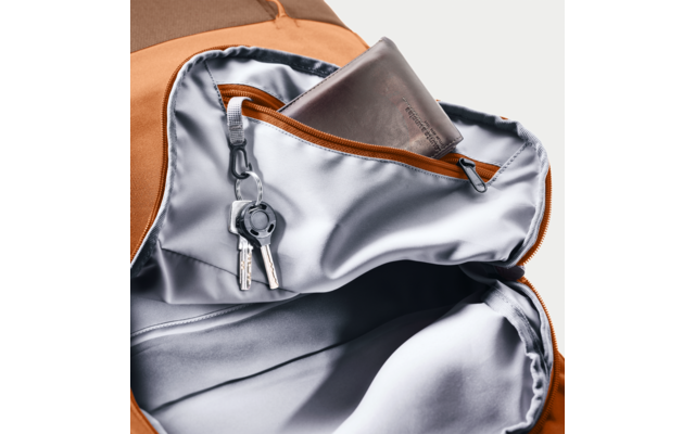 Offener orangefarbener Rucksack mit silberner Innentasche und Reißverschluss; braunes Lederportemonnaie in der Tasche, Schlüsselbund mit zwei Schlüsseln an einem Clip