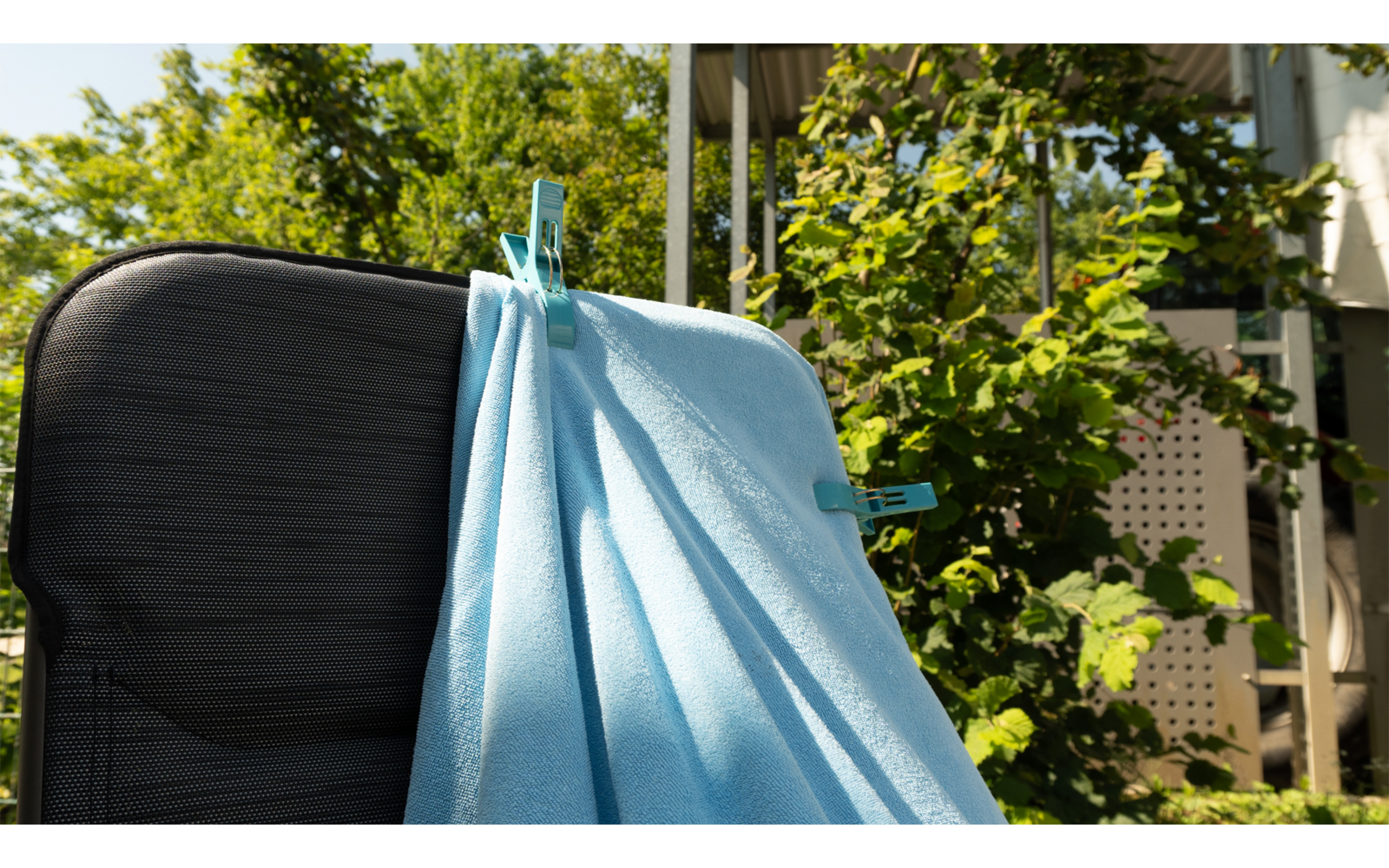 Blauer Mund-Nasen-Schutz hängt an einem schwarzen Koffergriff im Freien