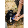 Des mains insèrent un connecteur bleu dans une bobine de câble noire sur de l'herbe sèche; pantalon et manche retroussée visibles