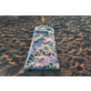 Tapis rectangulaire coloré à motif de feuilles posé sur du sable; sable avec empreintes et ombres