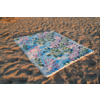 Serviette de plage rectangulaire à motif de feuilles bleu et rose posée à plat sur du sable